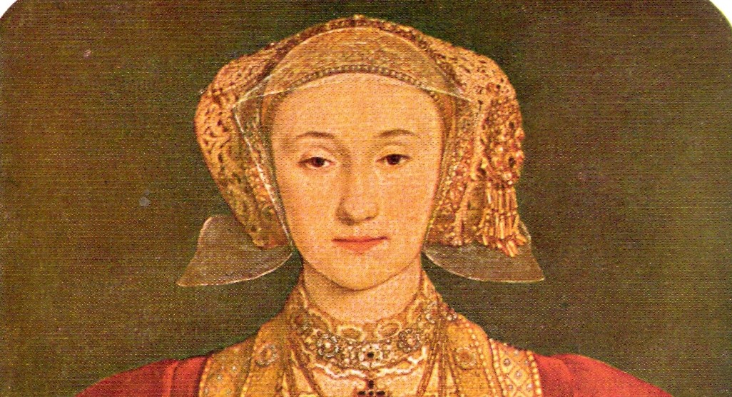 A cropped portion of the famous portrait of Anne of Cleves by Holbein, she wears a red and gold dress with a gold hood headdress. 